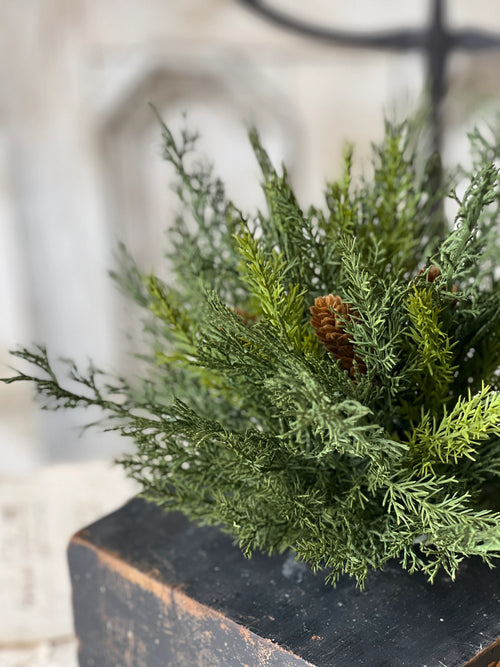Green artificial evergreen half sphere with pinecones on a wooden surface