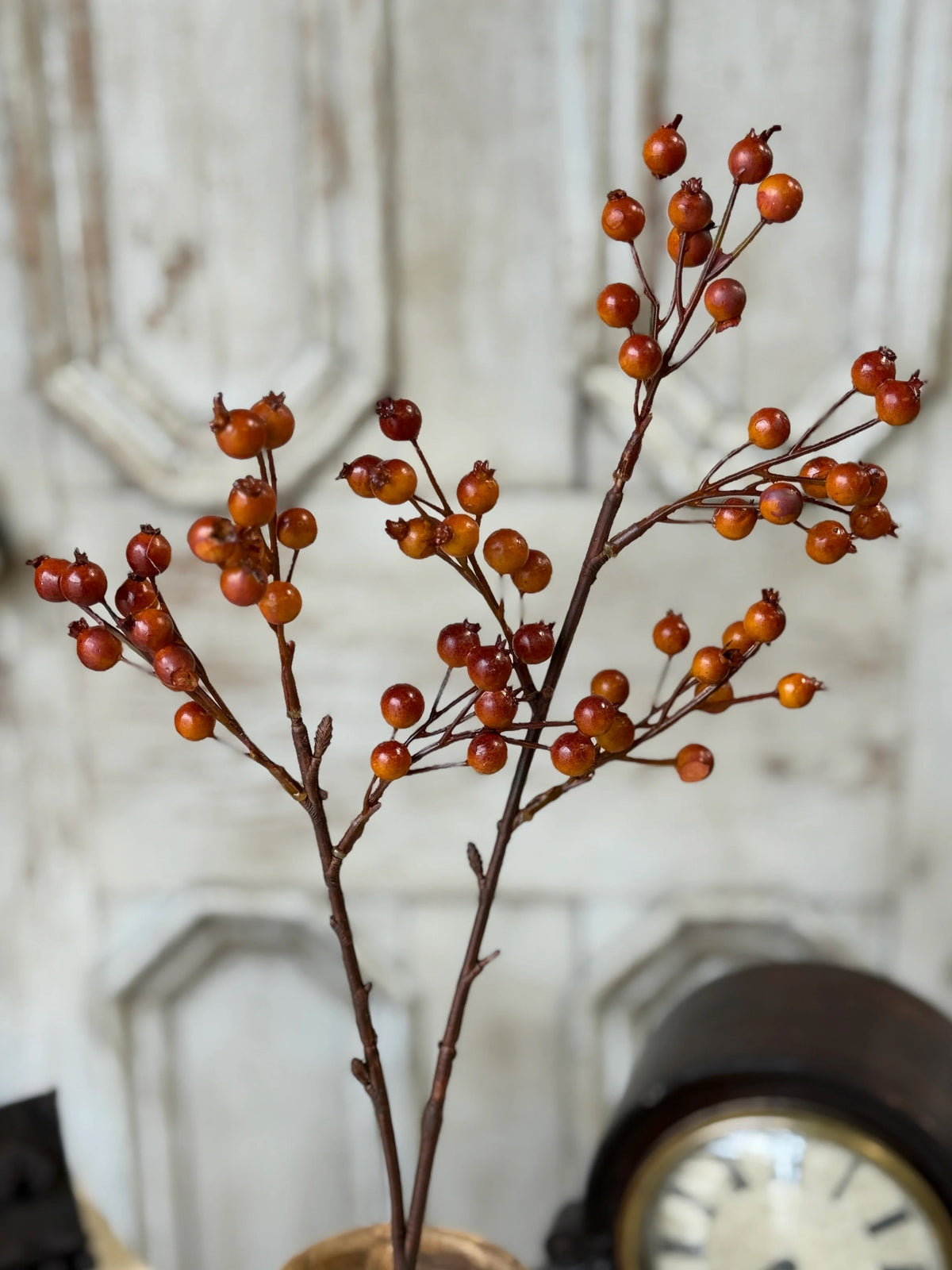 Artificial stem with red orange berries in a decorative setting