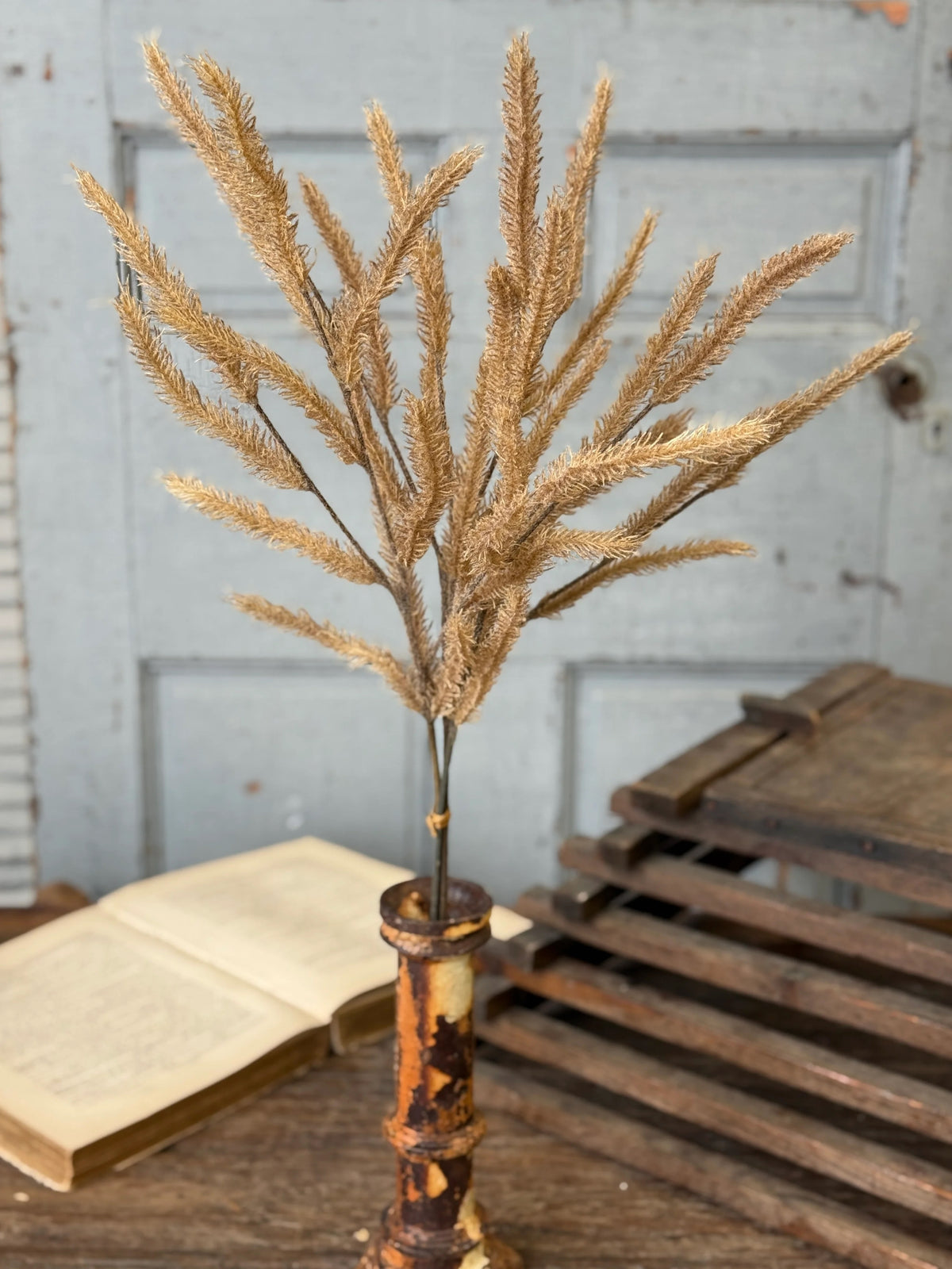 Decorative stem with dried branches in a rustic vase on a wooden surface.