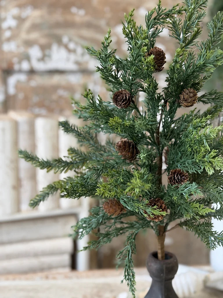 Artificial mixed evergreen stem with pinecones in a decorative setting