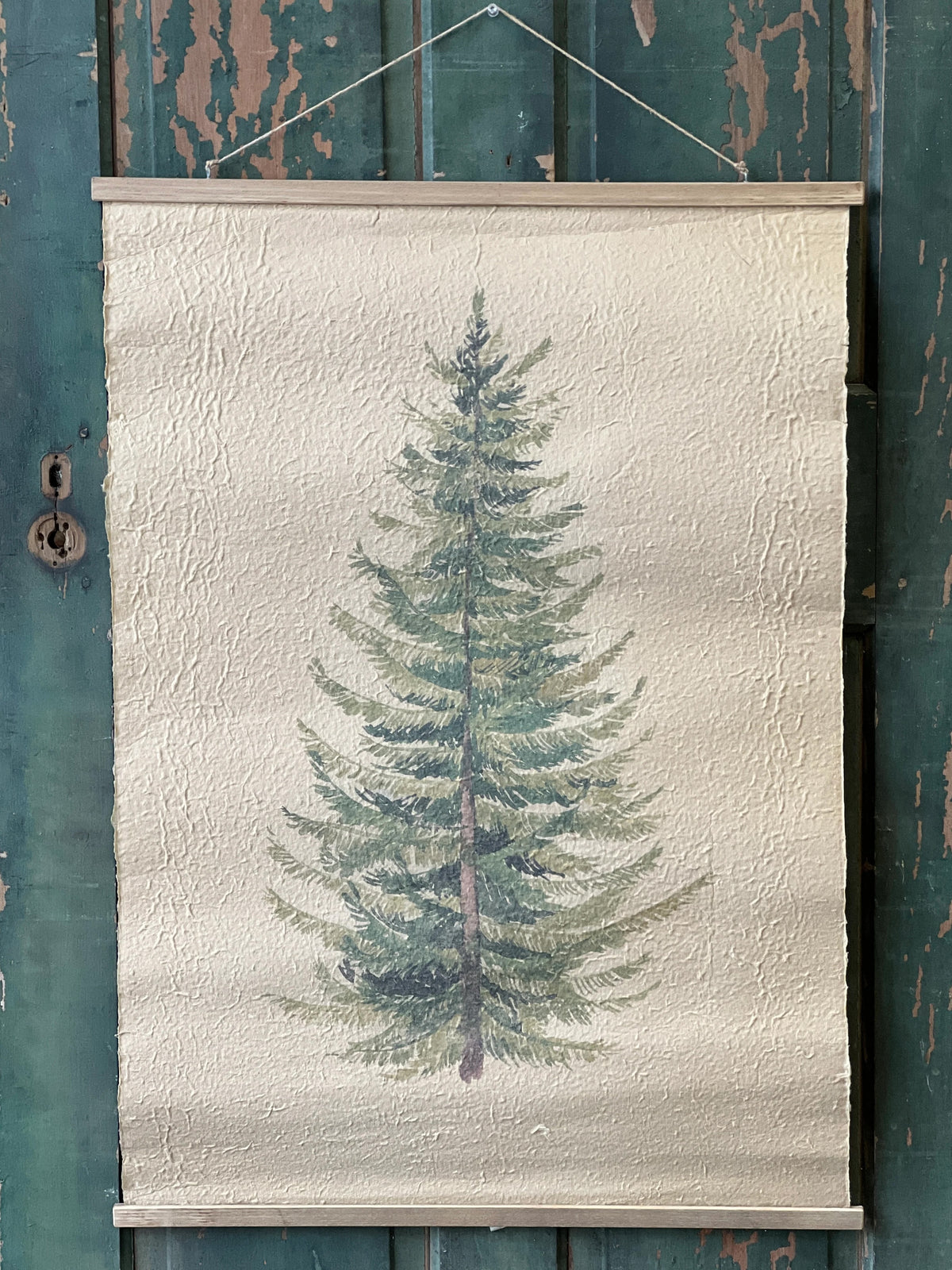 Textured paper scroll print of a pine tree hanging on a rustic wooden wall.