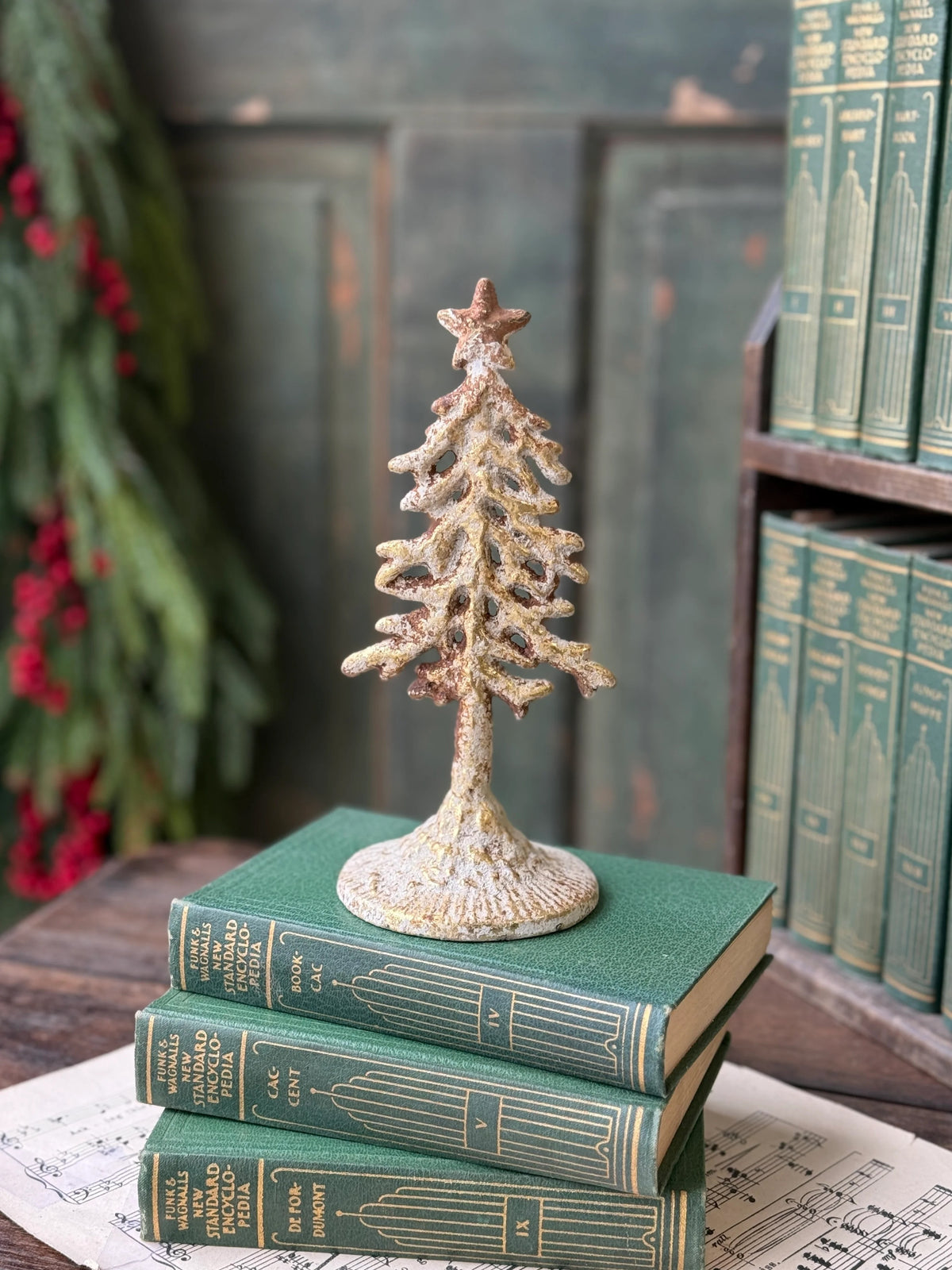 Decorative white washed gold metal Christmas tree on top of books with a rustic backgroundg
