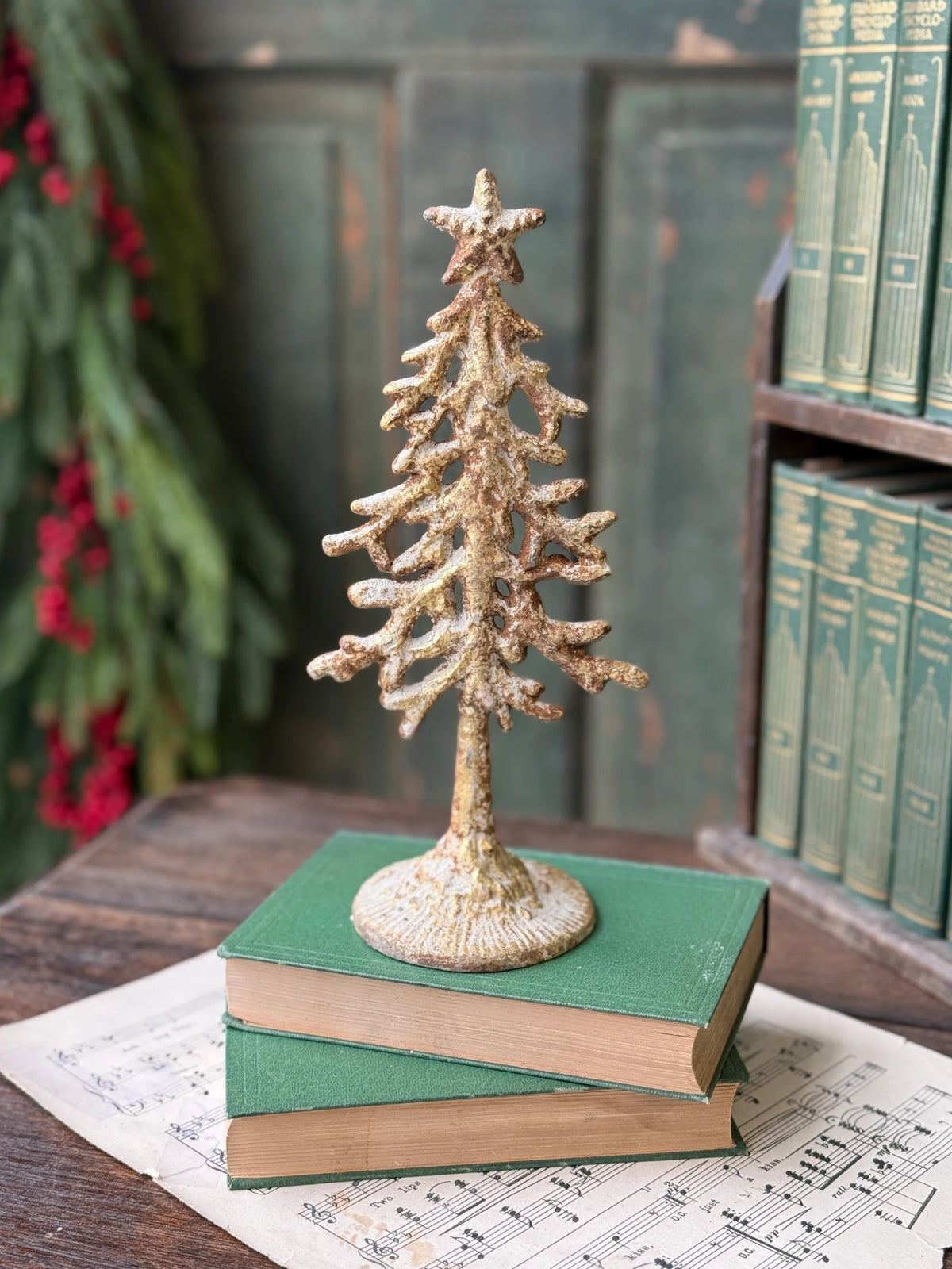 Decorative metal white washed gold Christmas tree on green books with a rustic background