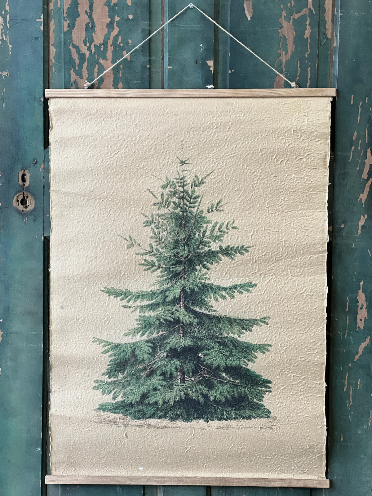 Hanging textured paper scroll of a pine tree on a textured white background, hanging against a rustic wooden wall.