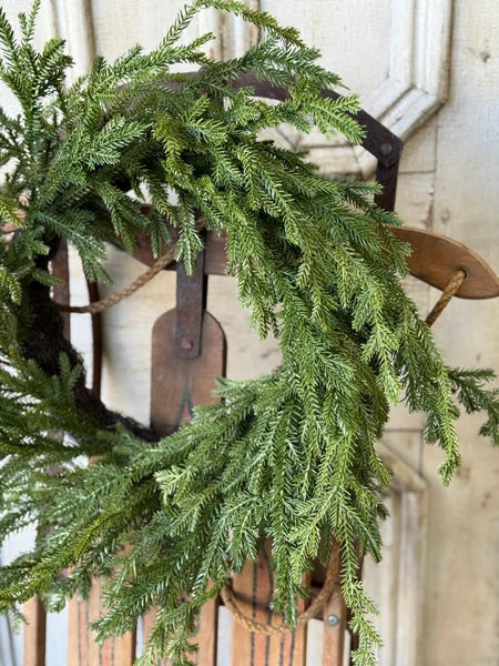 Green wreath on a vintage sled against a wooden door background