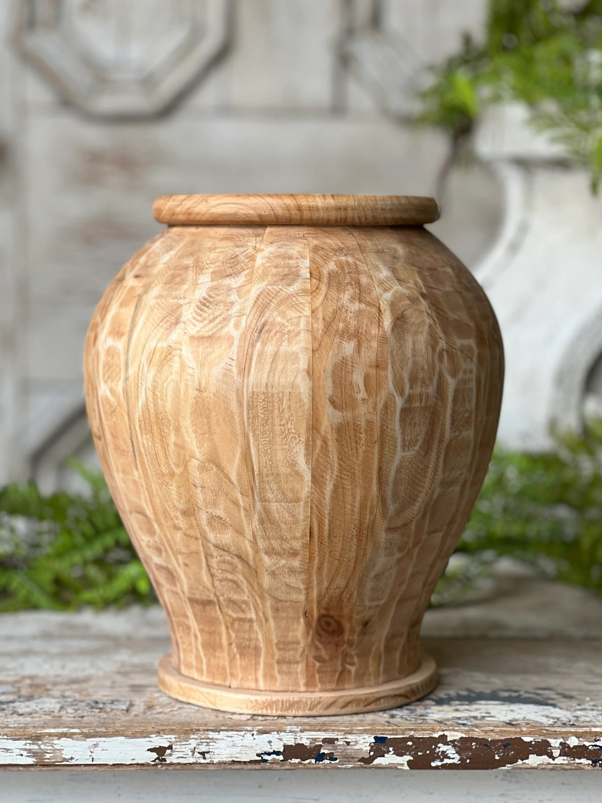 Wooden vase with textured surface on a rustic wooden surface with blurred background