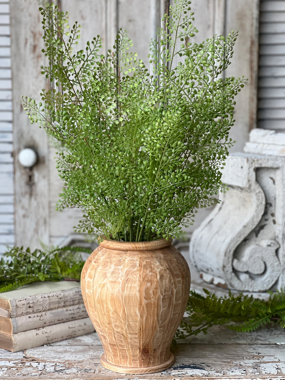 Decorative wooden vase with greenery on a rustic surface