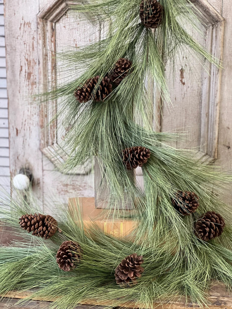 Green pine garland with pine cones on a wooden surface