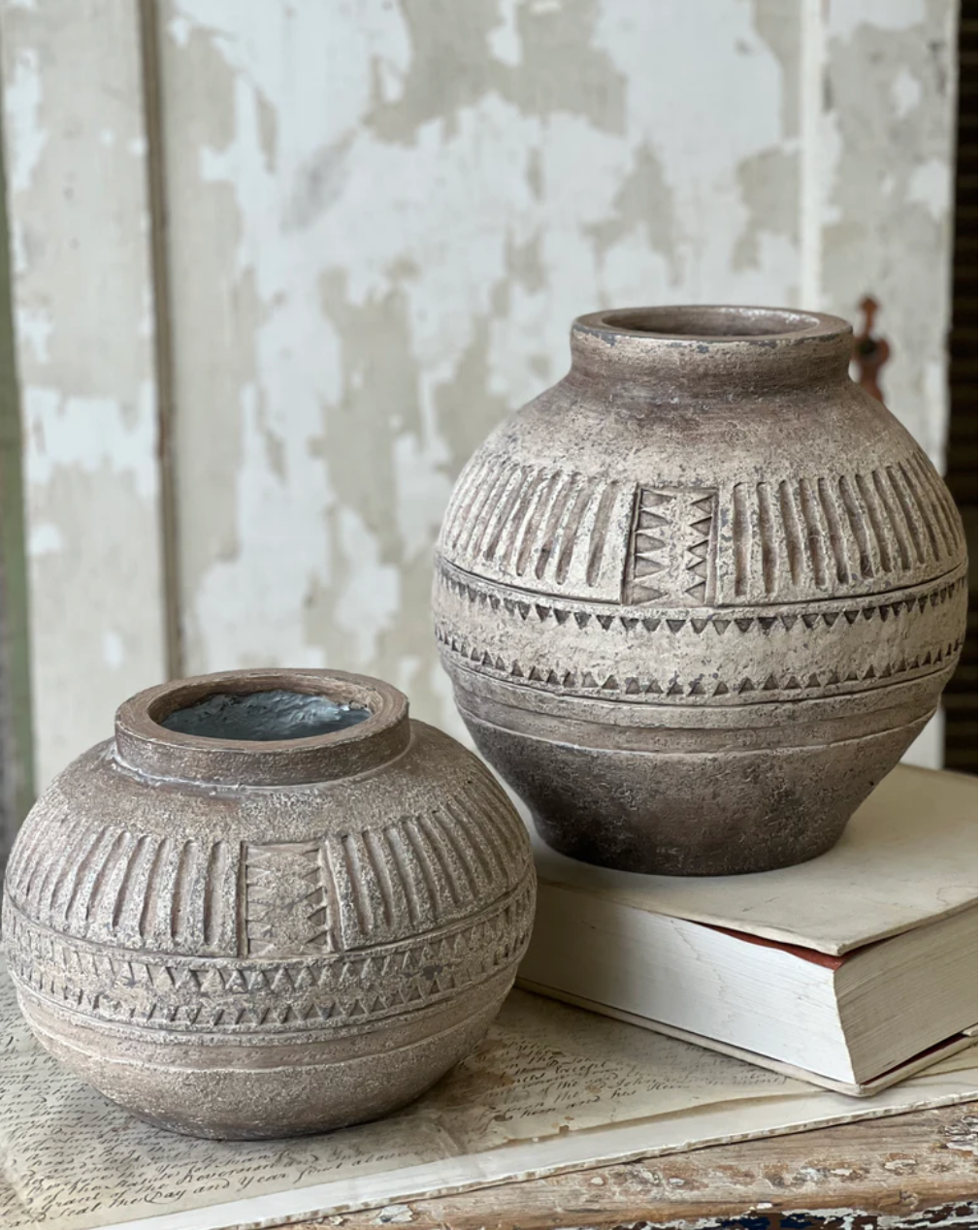 Two textured clay pots on a wooden surface with a neutral background