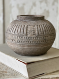 Textured ceramic vase on a stack of books with a neutral background