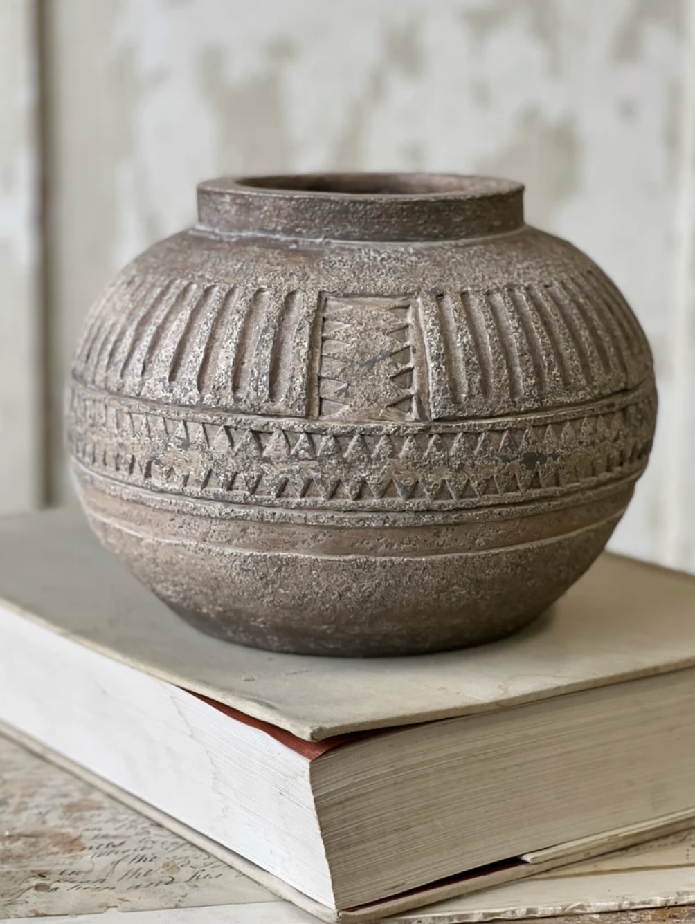 Textured ceramic vase on a stack of books with a neutral background