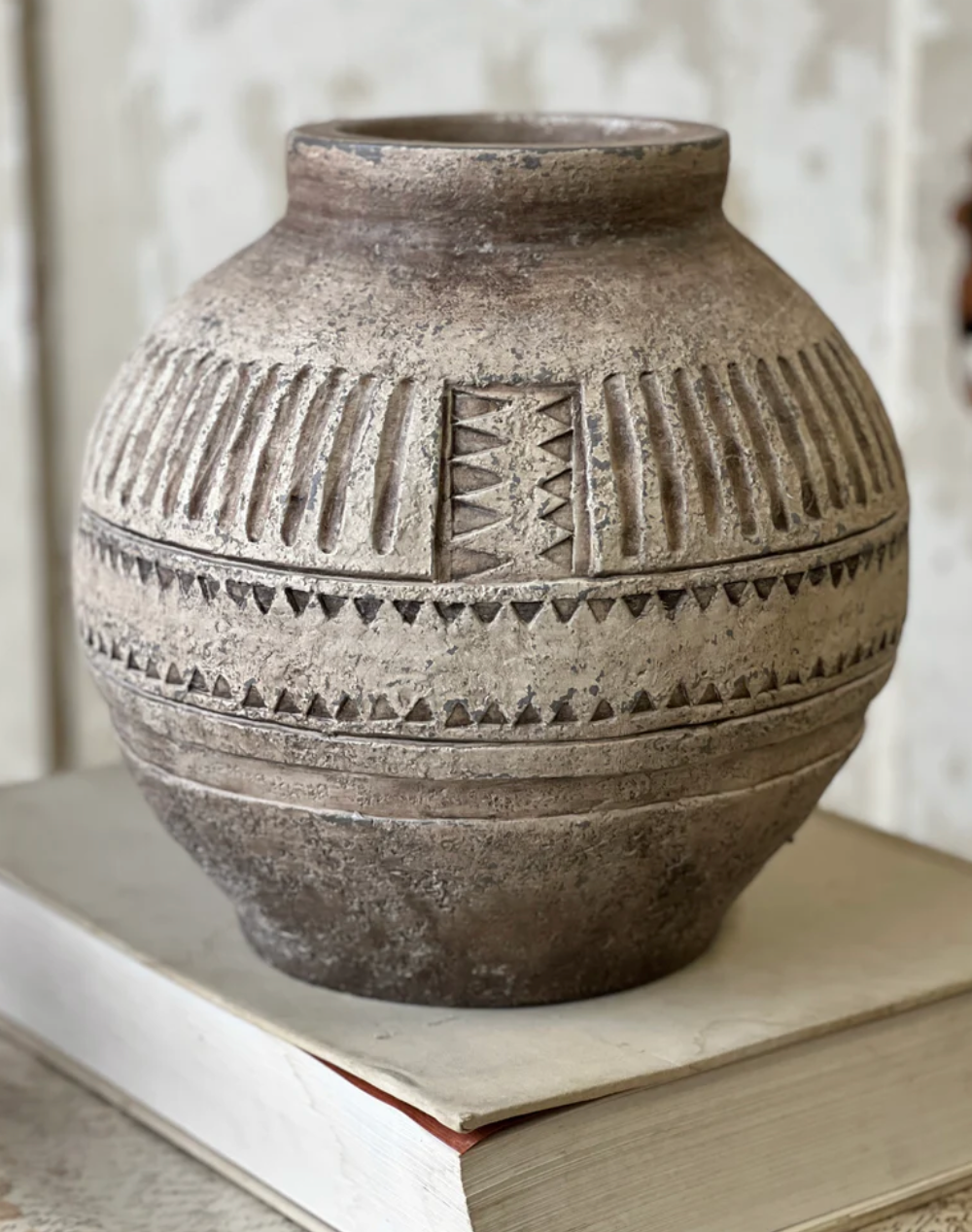 Decorative terracotta vase with geometric patterns on a wooden surface.