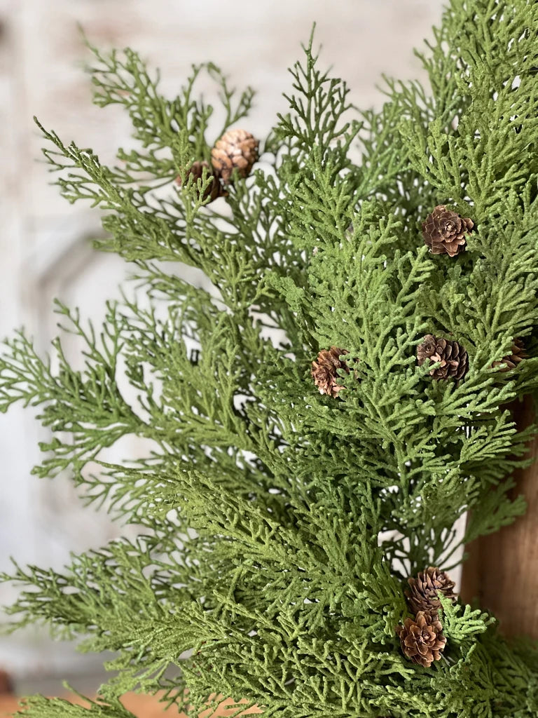 Close-up of a wreath green evergreen branches with small cones on a blurred background