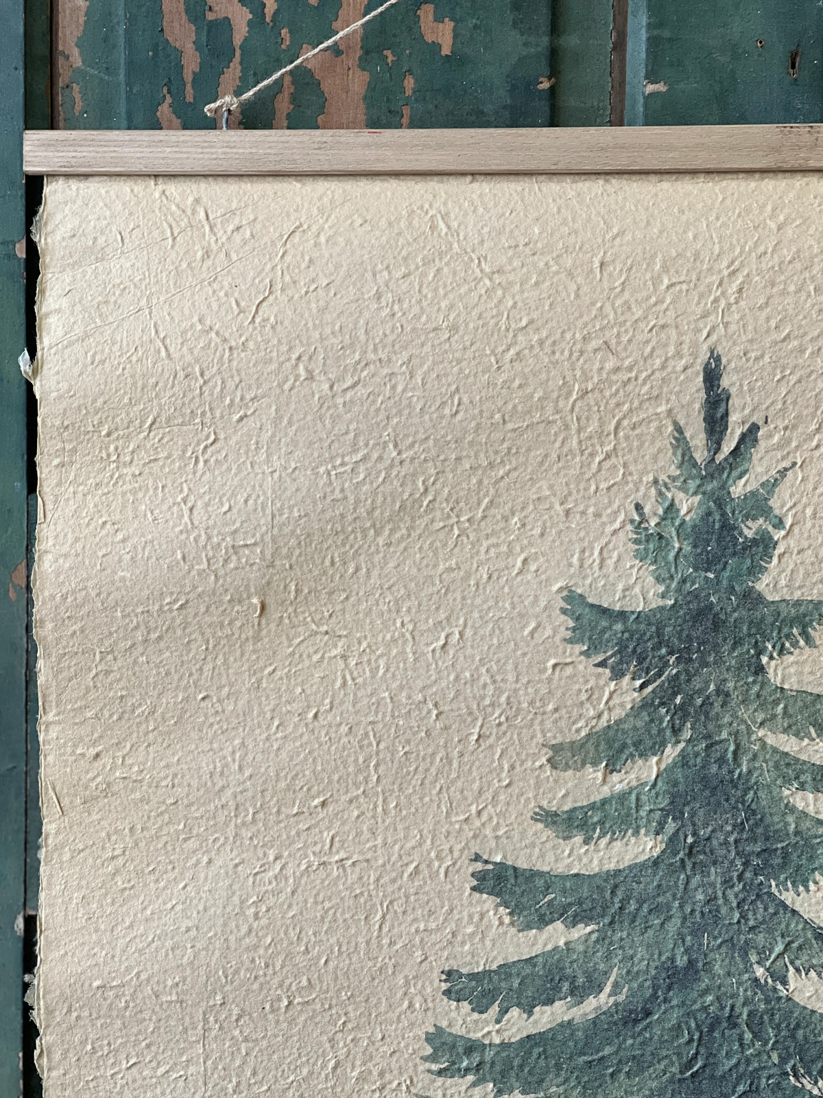 Textured paper print  with an evergreen tree silhouette against a blue door.