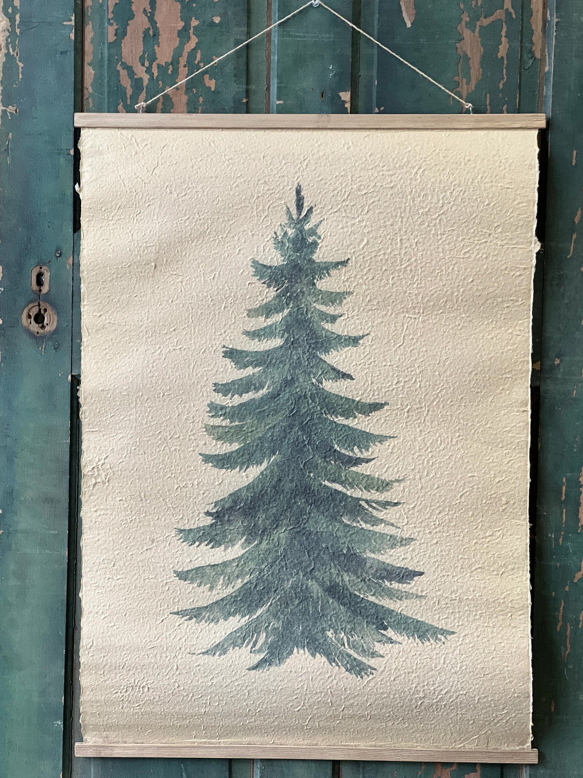 Textured paper print Framed of an evergreen green tree on a textured white background, hanging against a rustic wooden panel.