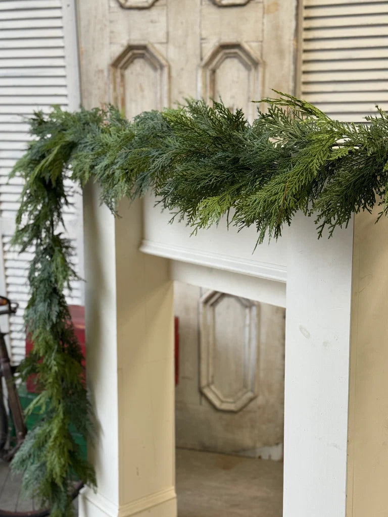 Green Christmas garland on a fireplace mantel with a neutral background