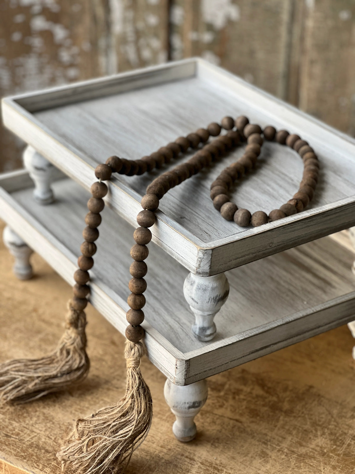 Wooden tray with a string of natural wood tone beads on a wooden surface
