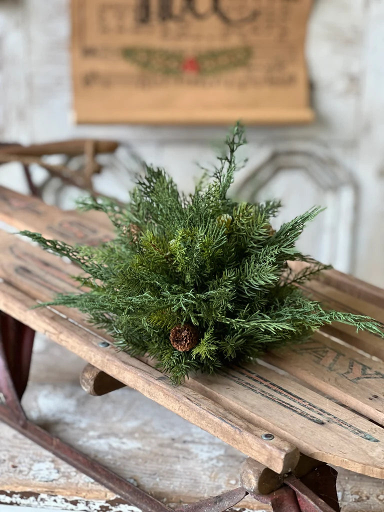 Evergreen greenery half sphere on a wooden sled with a rustic background
